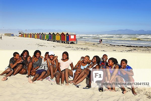 Happy black teenagers on the beach  colorful beach cottages  Muizenberg  False Bay  Western Cape  South Africa  Africa