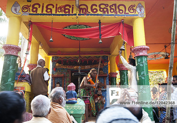 Schamane in stark verändertem Bewusstseinszustand bei der Durchführung eines Problemlösungsrituals für die in einem Hindu-Tempel versammelten Dorfbewohner  Odisha  Indien  Asien