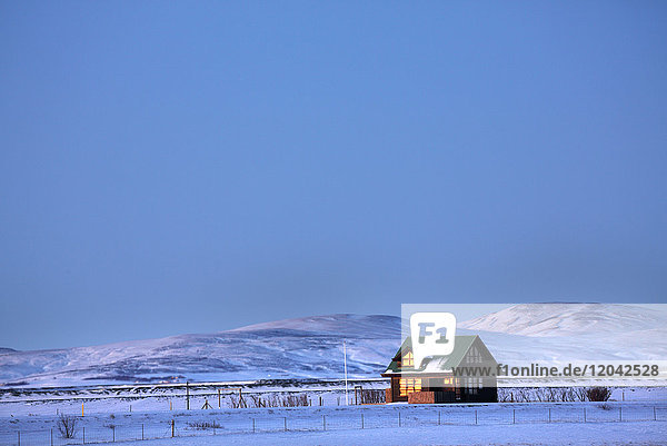 Winter landscape at dusk showing lone cabin bathed in evening sunlight near Seljalandsfoss South Iceland Polar Regions