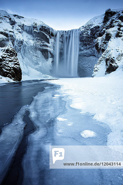 Winteransicht des Skogafoss-Wasserfalls  mit eiszapfenbedeckten Felsen und verschneitem Vorgelände  Skogar  Südisland  Polarregionen