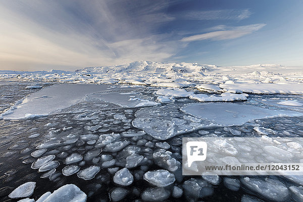 Gefrorene Jokulsarlon Gletscherlagune im Winter mit Eis im Vordergrund und schneebedeckten Bergen in der Ferne  Südisland  Polarregionen