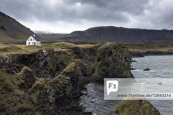 Einsames weißes Haus inmitten von Schornsteinen und Bergen bei Arnastapi  Snaefellsnes-Halbinsel  Island  Polarregionen