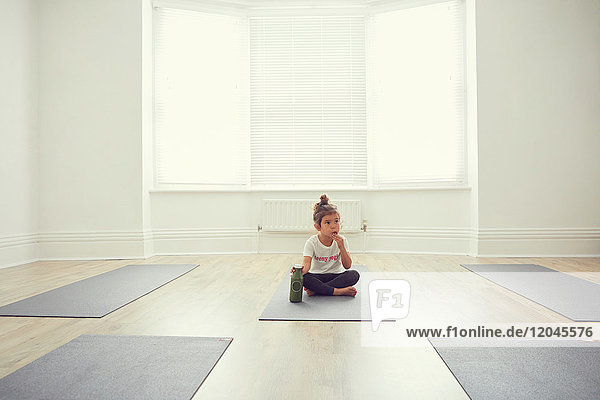 Young girl in yoga studio  sitting on yoga mat