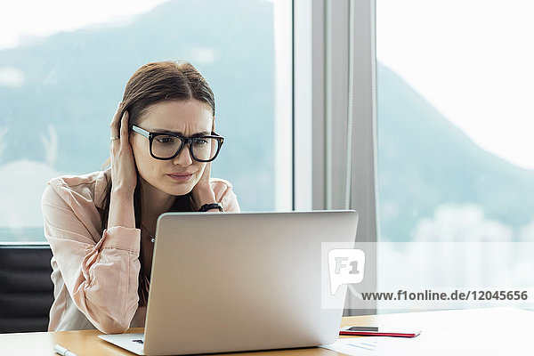 Frau mit Laptop  Kopf in Händen und gestresstem Blick