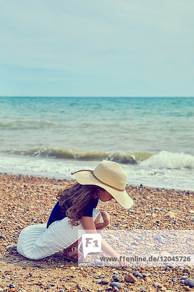 Young girl crouching on beach  collecting shells