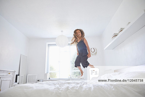 Young girl jumping on bed  low angle view