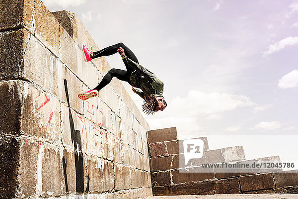 Junger Mann  freilaufend  im Freien  Salto von der Seite der Mauer
