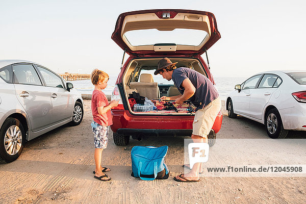 Father and son taking fishing rods from car boot Goleta California United States North America