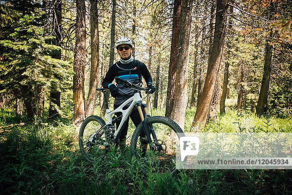 Man in forest with mountain bike looking at camera Mammoth Lake California USA North America