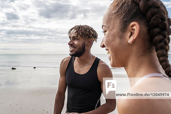 Young male and female runners smiling on beach