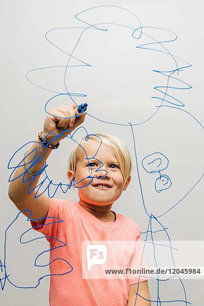 Boy drawing with marker pen onto glass wall