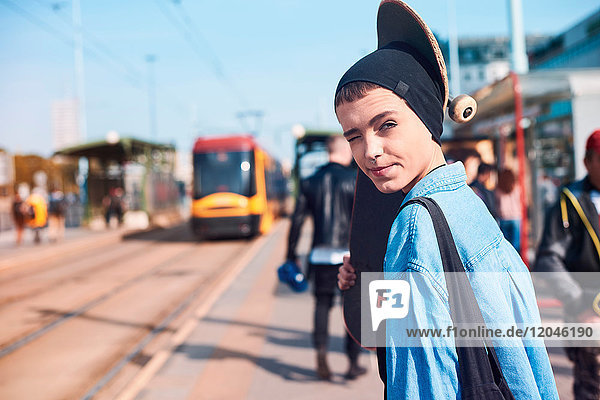 Porträt einer coolen jungen Skateboarderin mit Mützenmütze an der Straßenbahnhaltestelle