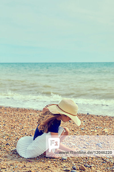 Young girl crouching on beach,  collecting shells