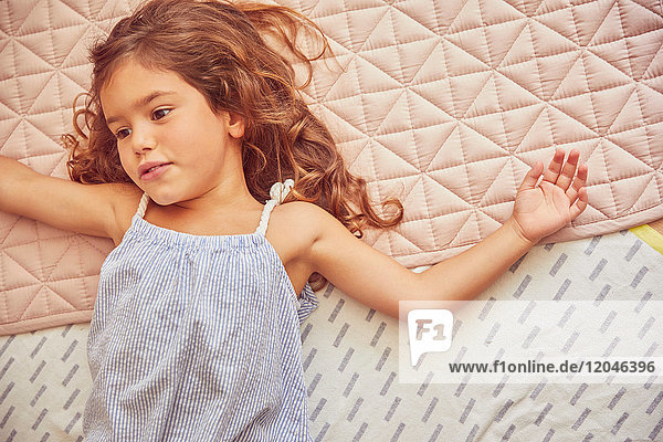 Young girl lying on bed  thoughtful expressions  overhead view