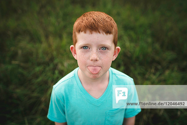 Porträt eines rothaarigen Jungen mit herausgestreckter Zunge