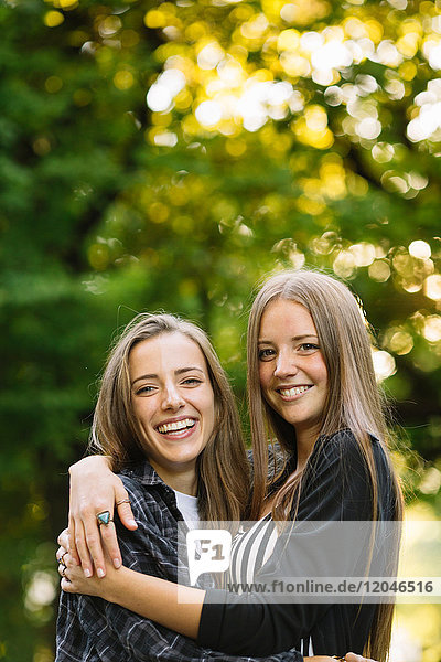 Porträt von zwei jungen Freundinnen  die sich im Park umarmen