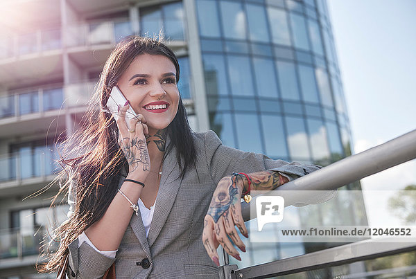 Geschäftsfrau im Freien  Smartphone benutzen  lächeln  Tätowierungen auf den Händen