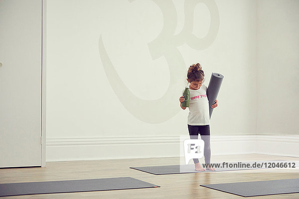 Young girl standing in yoga studio  holding yoga mat