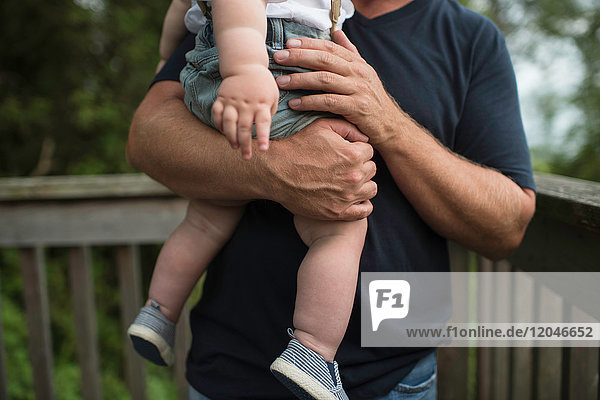 Mid section of man carrying toddler son on balcony