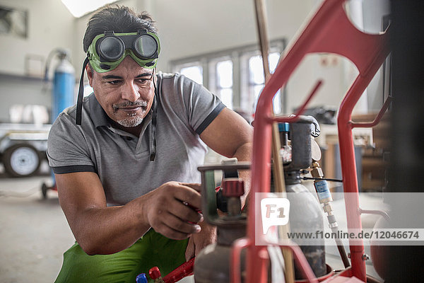 Mann bereitet Schweißvorrichtung in Karosserie-Reparaturwerkstatt vor