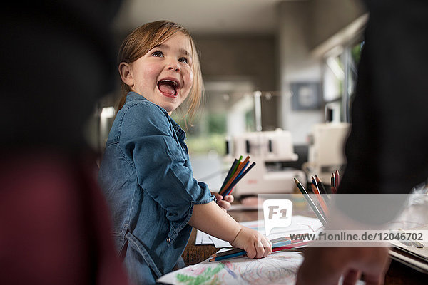 Mädchen und Vater wählen Farbstifte zum Zeichnen am Tisch