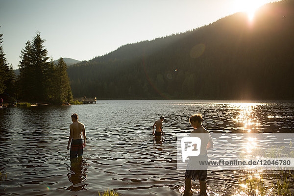 Drei Jungen im Teenager-Alter stehen im See  Rückansicht