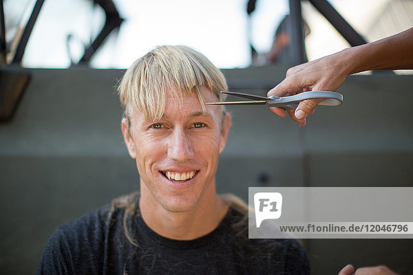 Porträt eines jungen Mannes beim Haareschneiden