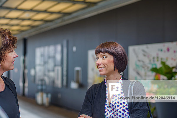 Woman in office chatting with colleagues smiling