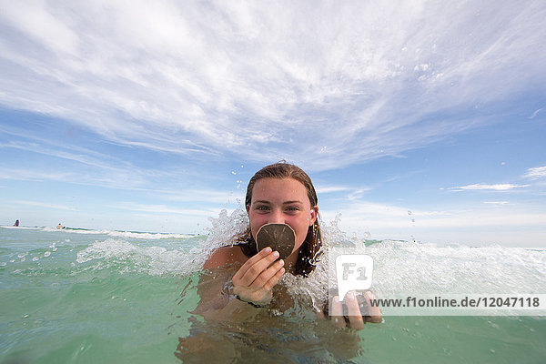 Porträt einer jungen Frau im Wasser  die Muscheln hält