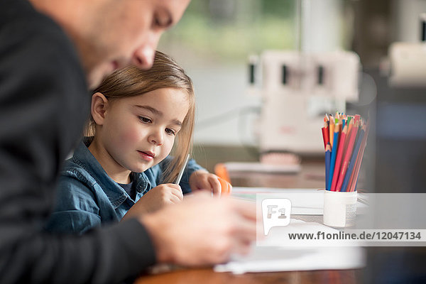 Junger Mann und seine Tochter beim Zeichnen am Tisch