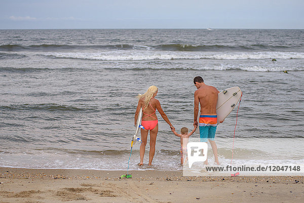 Rückansicht eines Surferpaares am Wasser mit Kleinkind-Tochter  Asbury Park  New Jersey  USA