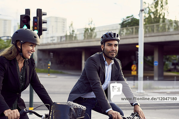 Lächelnde Geschäftsfreunde beim Radfahren in der Stadt