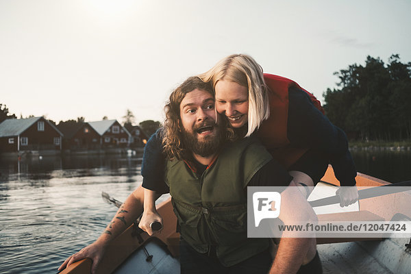 Happy couple enjoying in boat on lake against sky