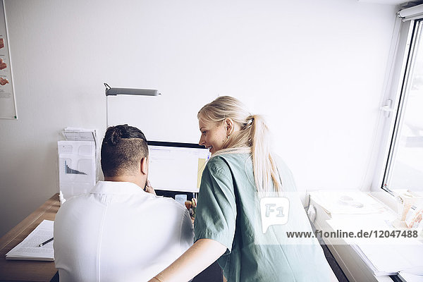 Rear view of female nurse and male doctor discussing at office in hospital