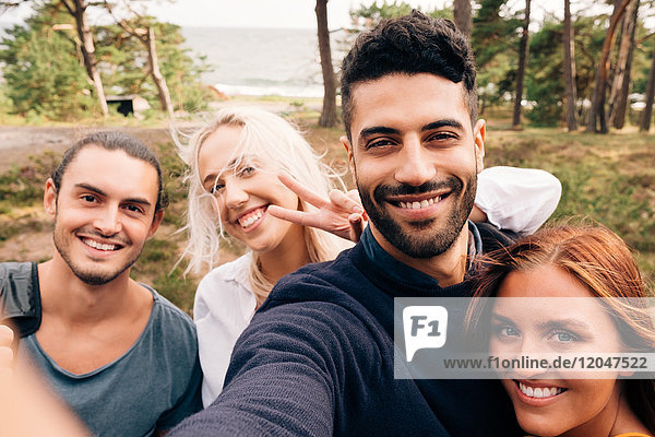 Glückliche männliche und weibliche Freunde  die Selfie im Wald nehmen.