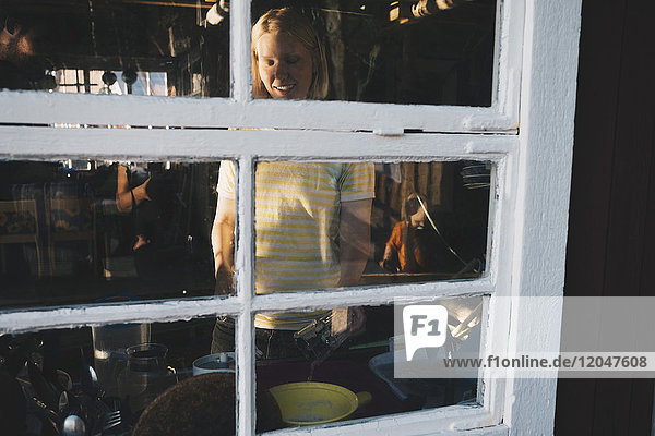 Lächelnde Frau beim Kochen vom Glasfenster aus gesehen