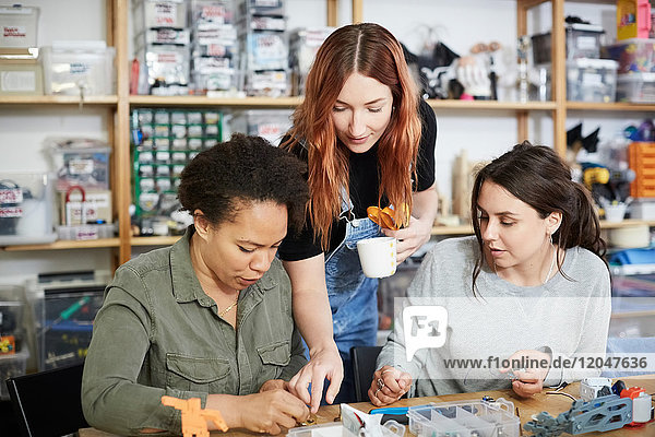 Redhead technician pointing to female coworkers at workshop