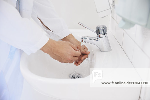 Ausschnitt eines männlichen Arztes  der sich im Krankenhaus die Hände wäscht.