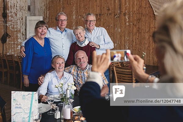 Seniorin fotografiert glückliche Freunde am Tisch im Restaurant