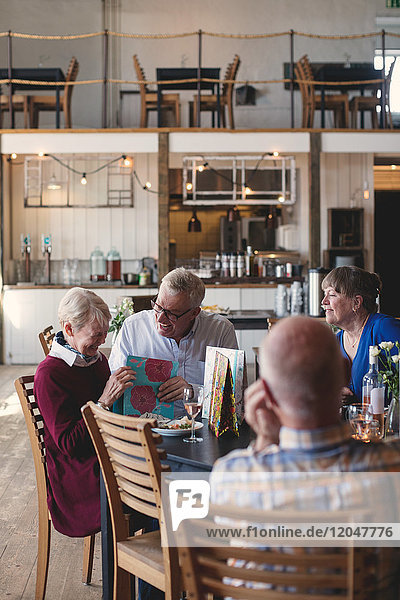 Fröhliches Seniorenpaar beim Mittagessen mit Freunden im Restaurant
