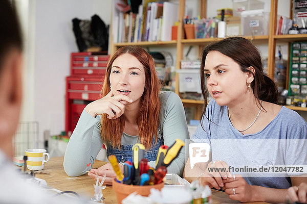 Female technicians sitting at table in workshop