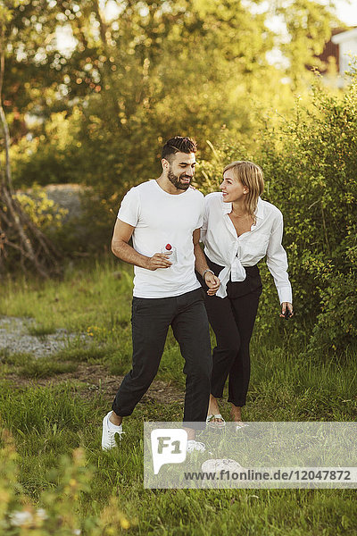 Lächelndes junges Paar beim Spaziergang auf dem Grasfeld