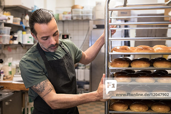 Sicherer  reifer  männlicher Besitzer mit Metallgestell in der Bäckereiküche
