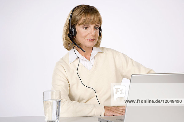 Frau mit Headset und Laptop-Computer