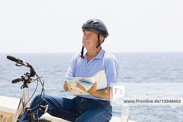 Mann mit Fahrrad und Karte am Wasser