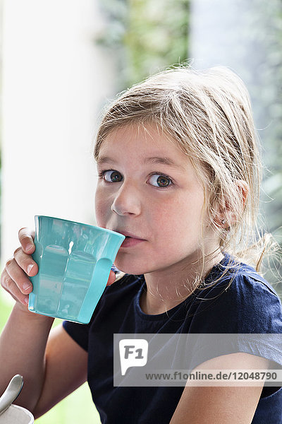 Mädchen trinkt aus blauem Becher