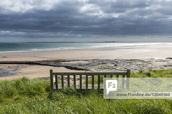 Holzbank auf der Dünenheide mit Blick auf den Strand und die Nordsee in Bamburgh in Northumberland  England  Vereinigtes Königreich