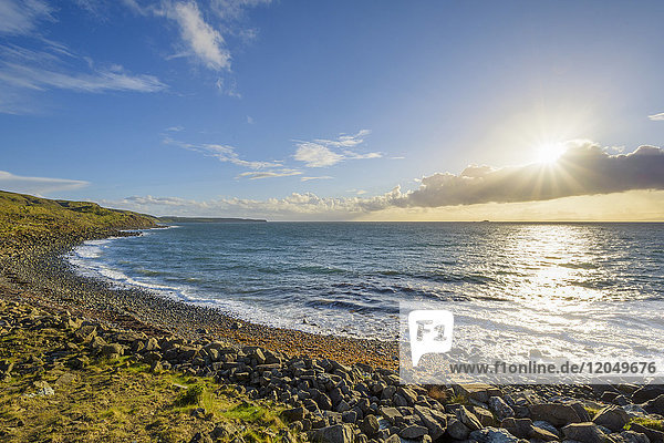 Felsiger Küstenstrand mit Sonnenschein über dem Meer auf der Isle of Skye in Schottland  Vereinigtes Königreich