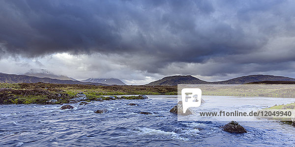 River in moor landscape with dark storm clouds and mountains in the background at Rannoch Moor in Scotland  United Kingdom