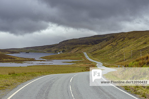 Kurvenreiche Küstenstraße und typisch schottische Landschaft auf der Halbinsel Trotternish auf der Isle of Skye in Schottland  Vereinigtes Königreich